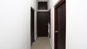 A narrow hallway with dark wooden doors and white walls. - OYO 11569 Jalan Lake View (Kolkata)