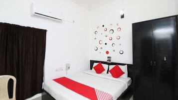A neatly arranged hotel room with a bed, a wardrobe, a wall-mounted air conditioner, and a telephone.