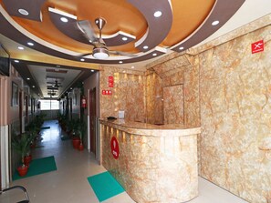 A hotel reception area with a marble reception desk, a ceiling fan, and a fire extinguisher. - OYO 13234 Hotel Mahak (Lucknow)