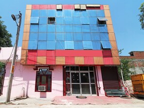 A building with a large glass facade, a red and blue color scheme, and a visible entrance with a door and windows. - OYO 13234 Hotel Mahak (Lucknow)