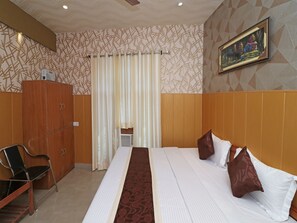 A hotel room with a bed, a wooden wardrobe, a chair, a curtain, and a painting on the wall. - OYO 13234 Hotel Mahak (Lucknow)