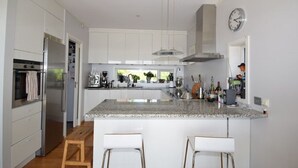 Cozinha moderna com armários brancos, bancada de granito e eletrodomésticos de aço inoxidável.