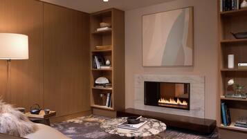 A modern living room with a fireplace, a sofa, a coffee table, and bookshelves.