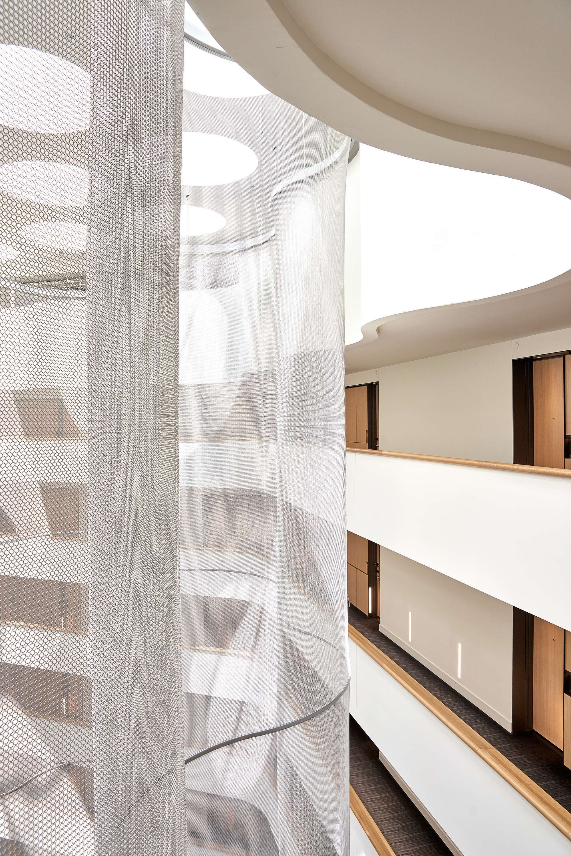 A multi-level interior with a modern design, featuring a central atrium with a glass ceiling and a series of balconies.