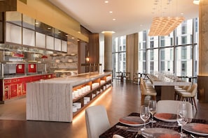 Comedor moderno de hotel con barra de mármol, asientos y ventanas amplias.