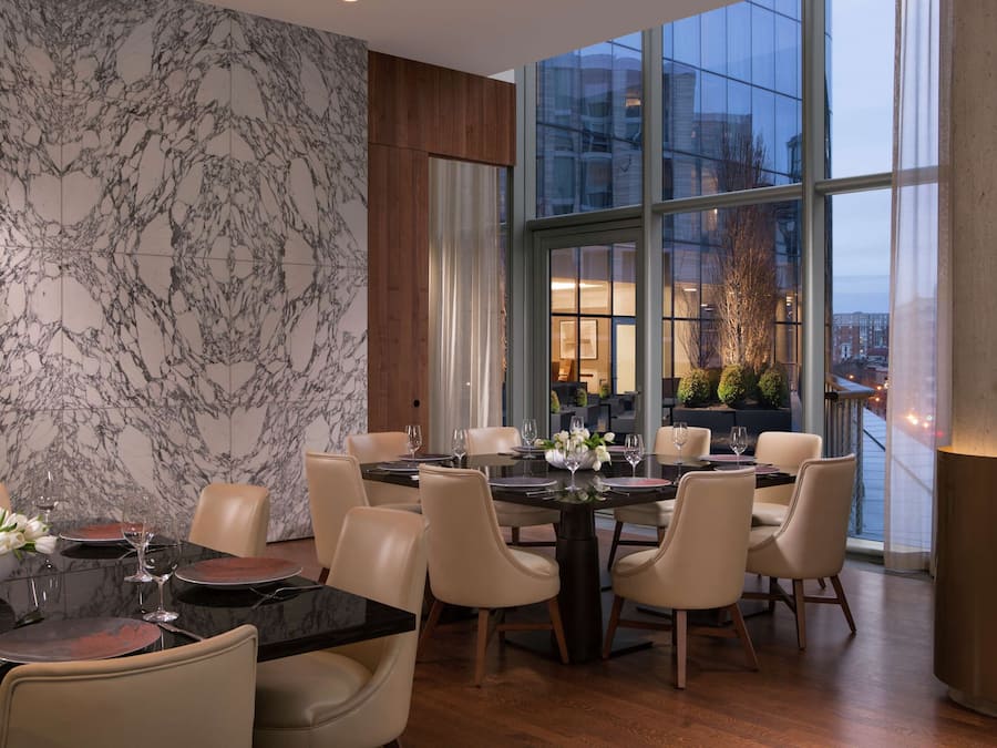 A modern dining area with a marble wall, a large window, and a view of the cityscape.