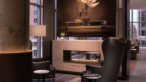 A modern lobby with a fireplace, seating area, and a large window offering a city view.
