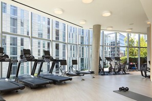Un gimnasio moderno con cintas de correr, bicicletas estáticas y pesas.