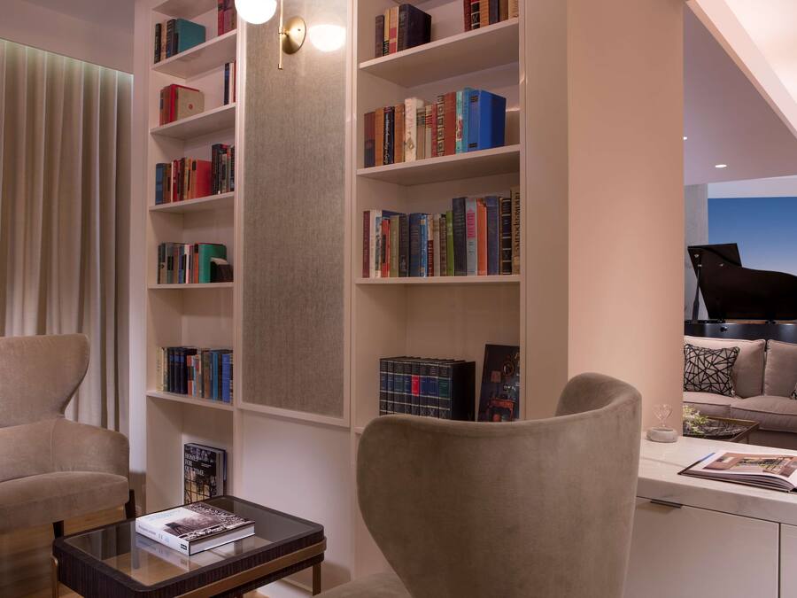 A modern living room with a large bookshelf, a piano, and comfortable seating.