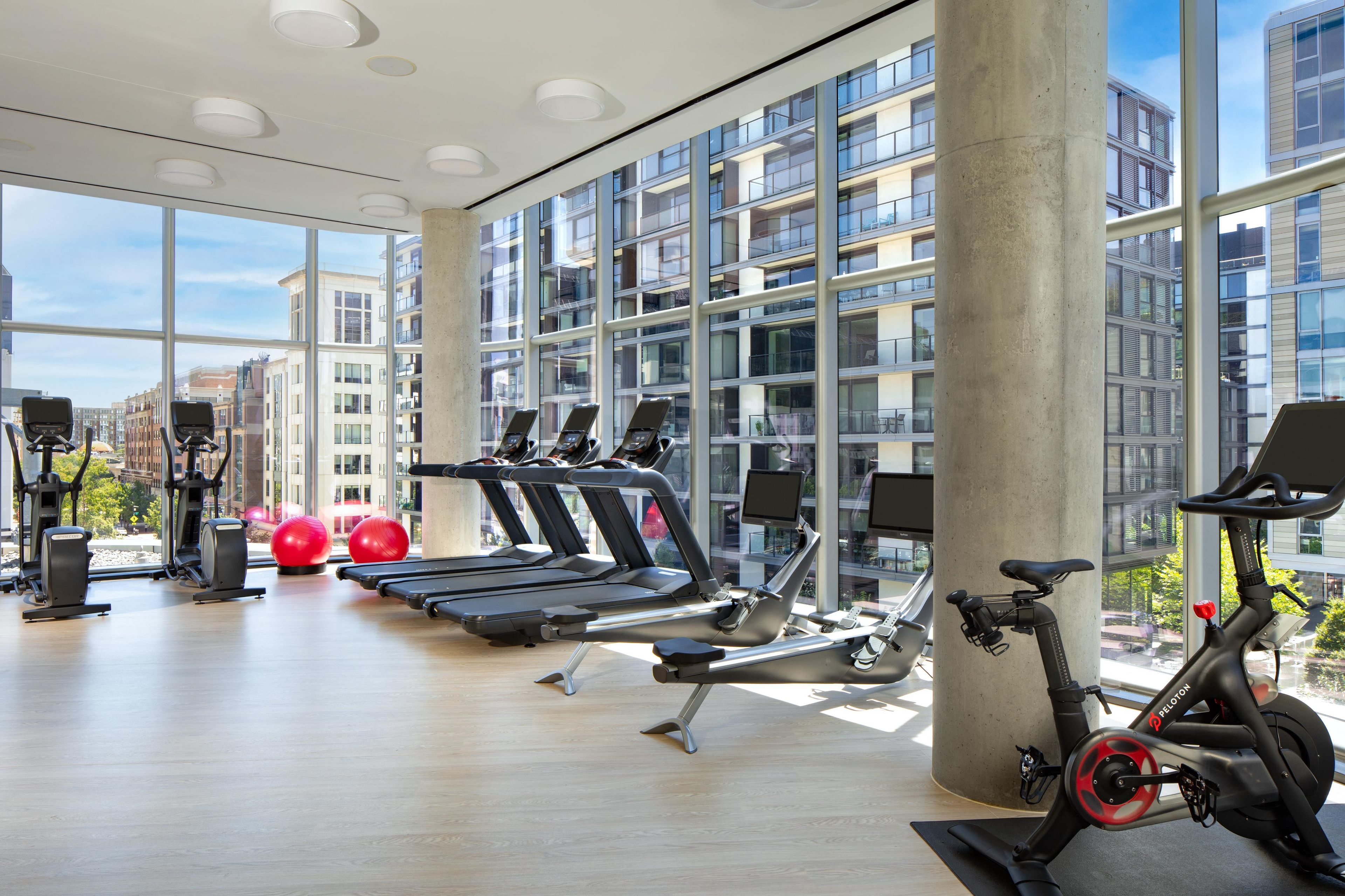 Un gimnasio moderno con equipamiento de ejercicio, ventanas amplias y vistas a la ciudad.