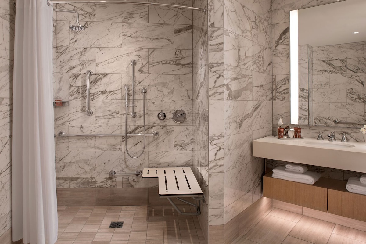 A modern bathroom with a shower, a vanity with a mirror, and a towel rack.