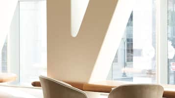 Un intérieur moderne avec deux fauteuils, un plafond haut et de grandes fenêtres qui laissent entrer la lumière naturelle.