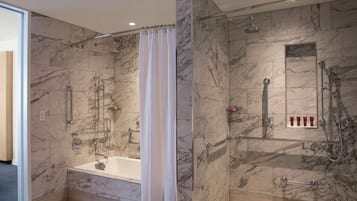 Une salle de bain moderne avec une douche à parois de verre, une baignoire et des murs en marbre.