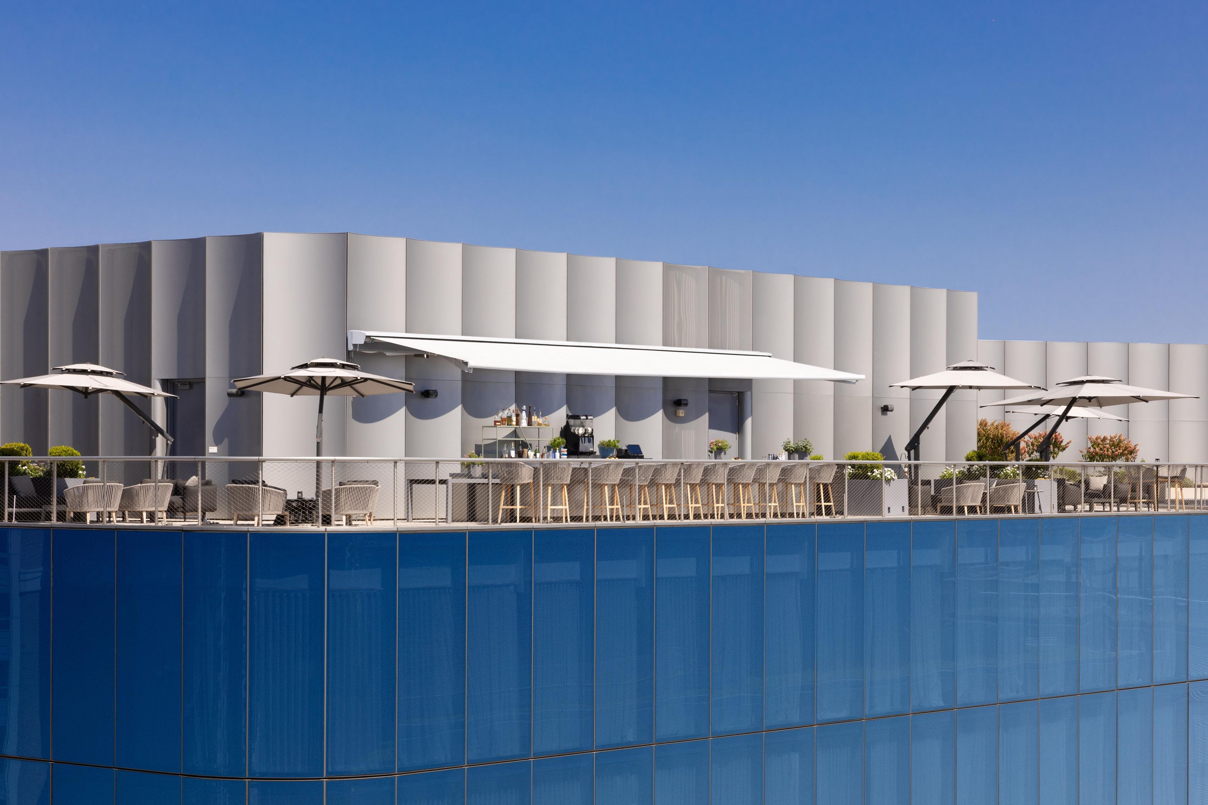 A modern building with a poolside area featuring outdoor seating and umbrellas.