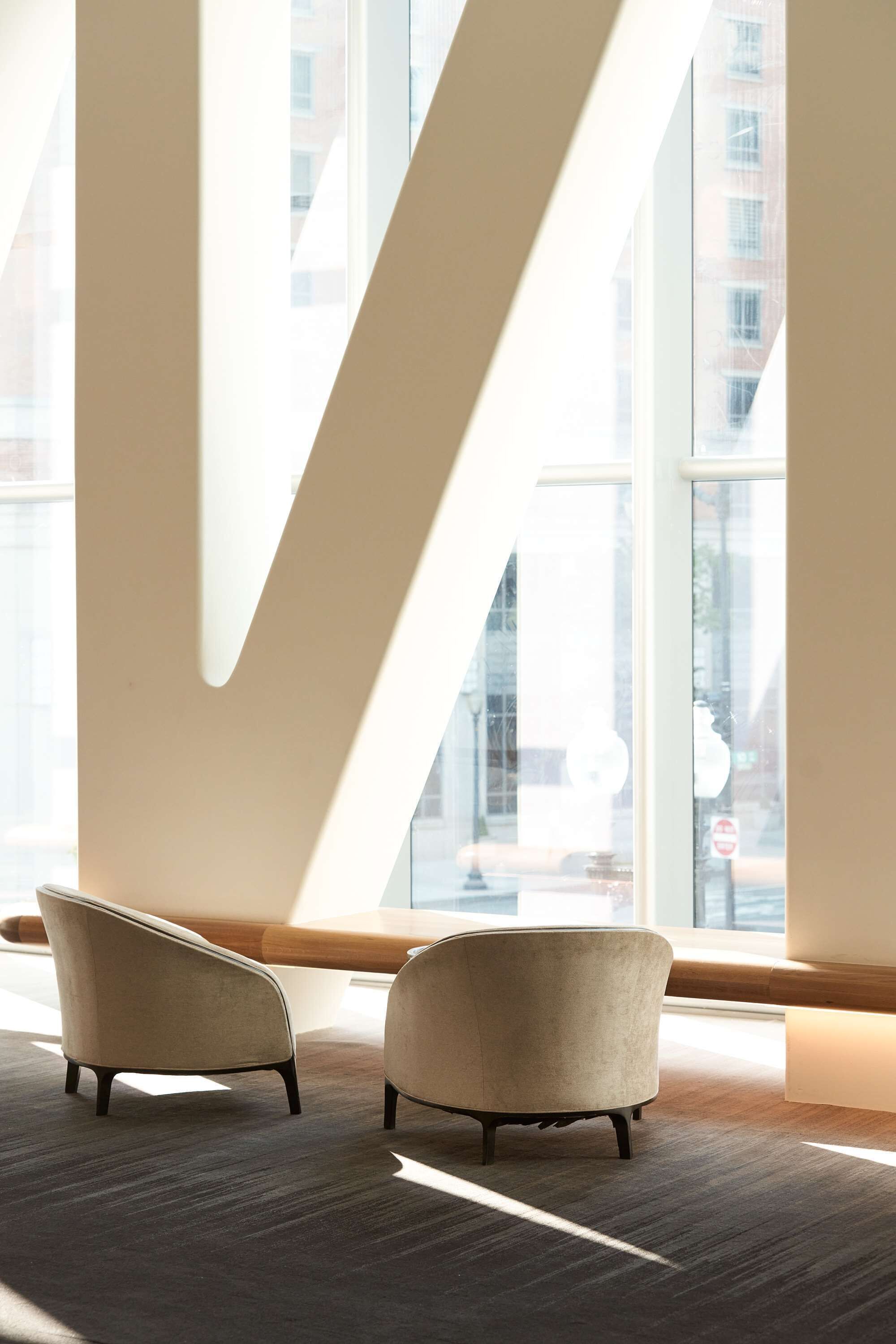 Un interior moderno con dos sillones cerca de amplias ventanas, que ofrecen vistas a un paisaje urbano.