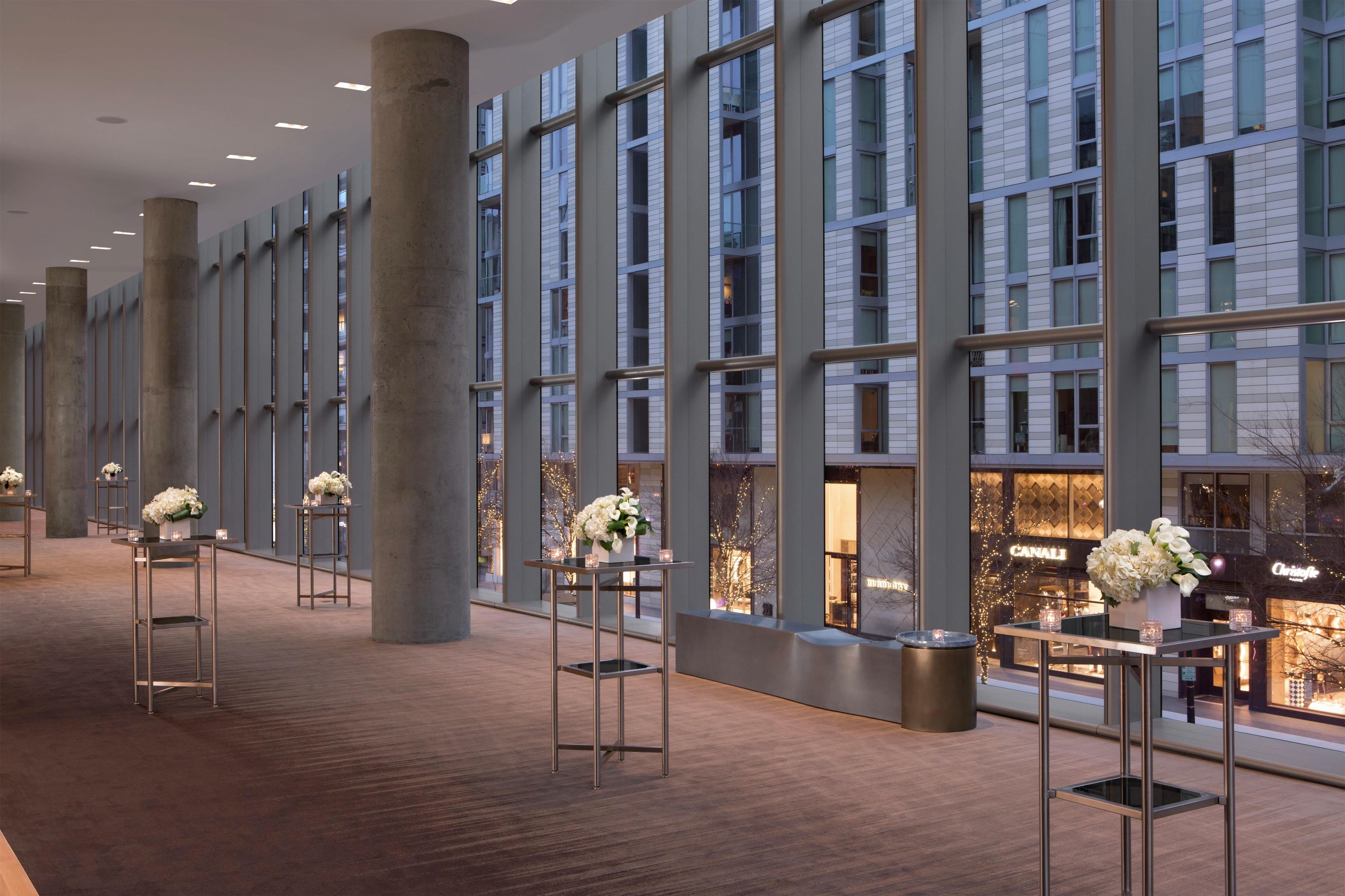 Een moderne hotellobby met hoge plafonds, grote ramen en een gepolijste houten vloer.