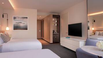 A hotel room with two beds, a TV, a desk, and a bathroom visible through an open door.