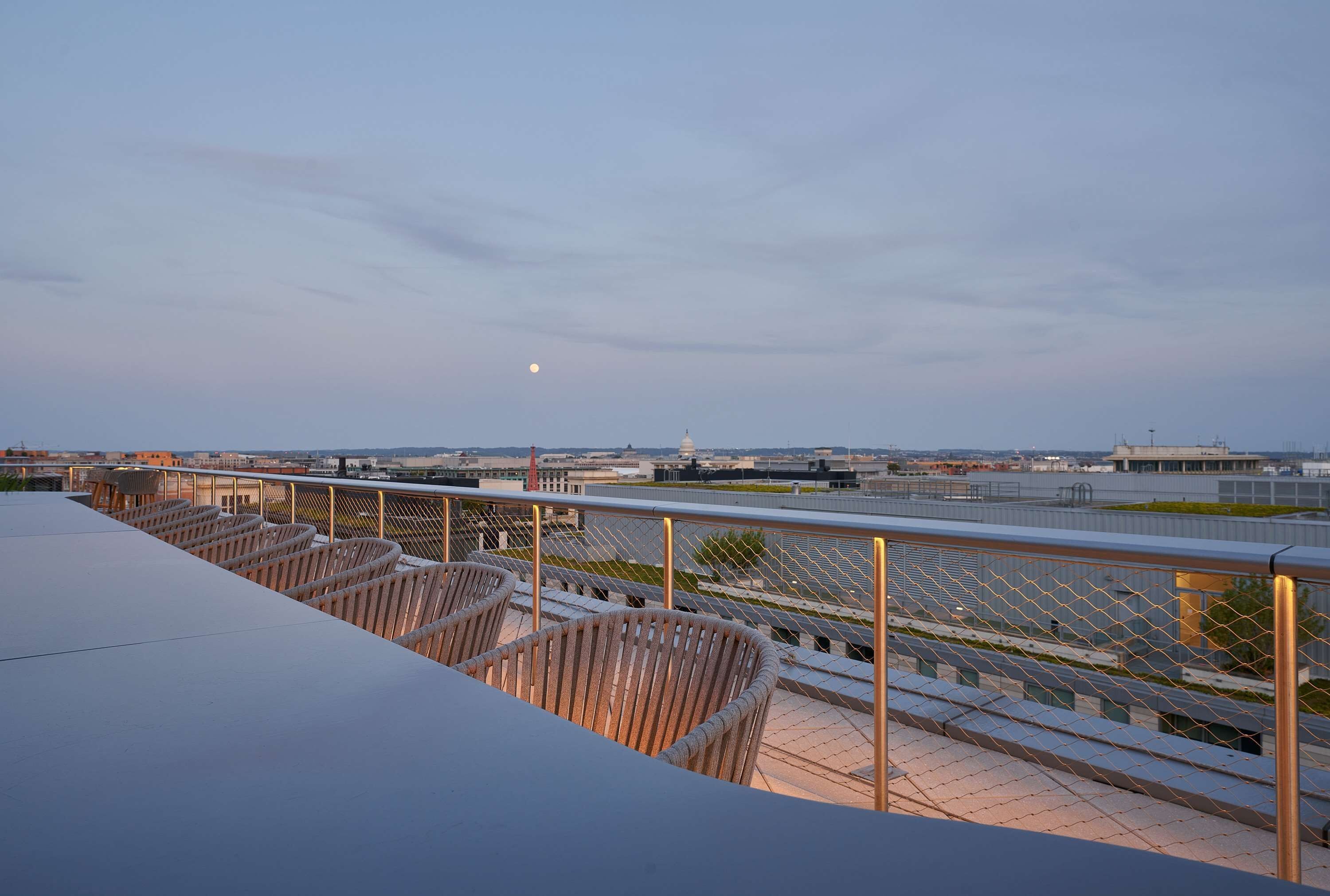 A rooftop terrace with seating and a view of the airport and cityscape.