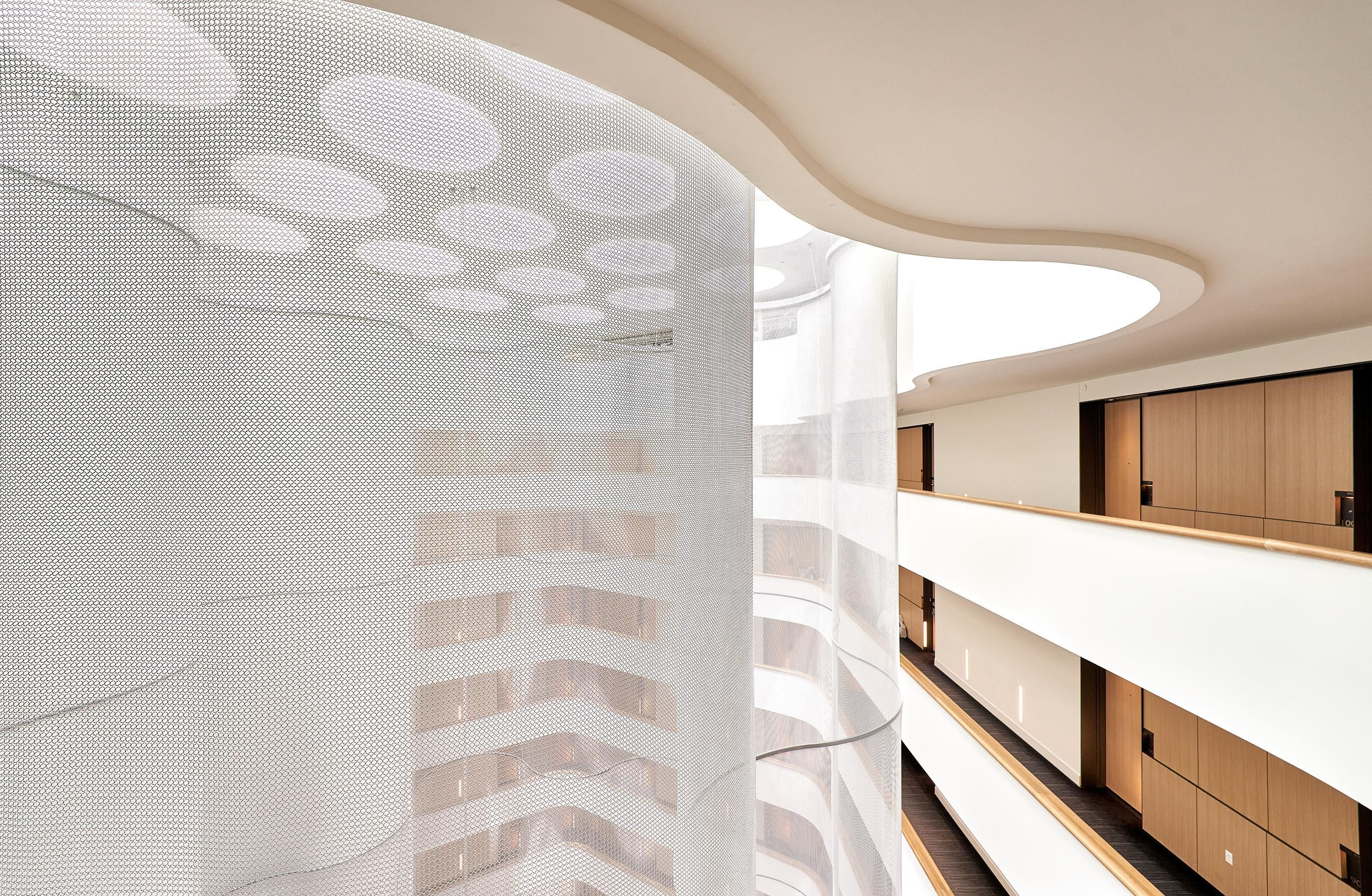 A modern interior with a curved ceiling, a long white counter, and wooden cabinets.