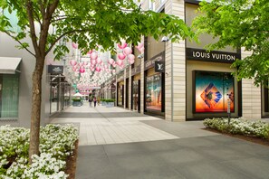 Un centro comercial moderno con una tienda Louis Vuitton, barandillas de vidrio y faroles decorativos colgantes.