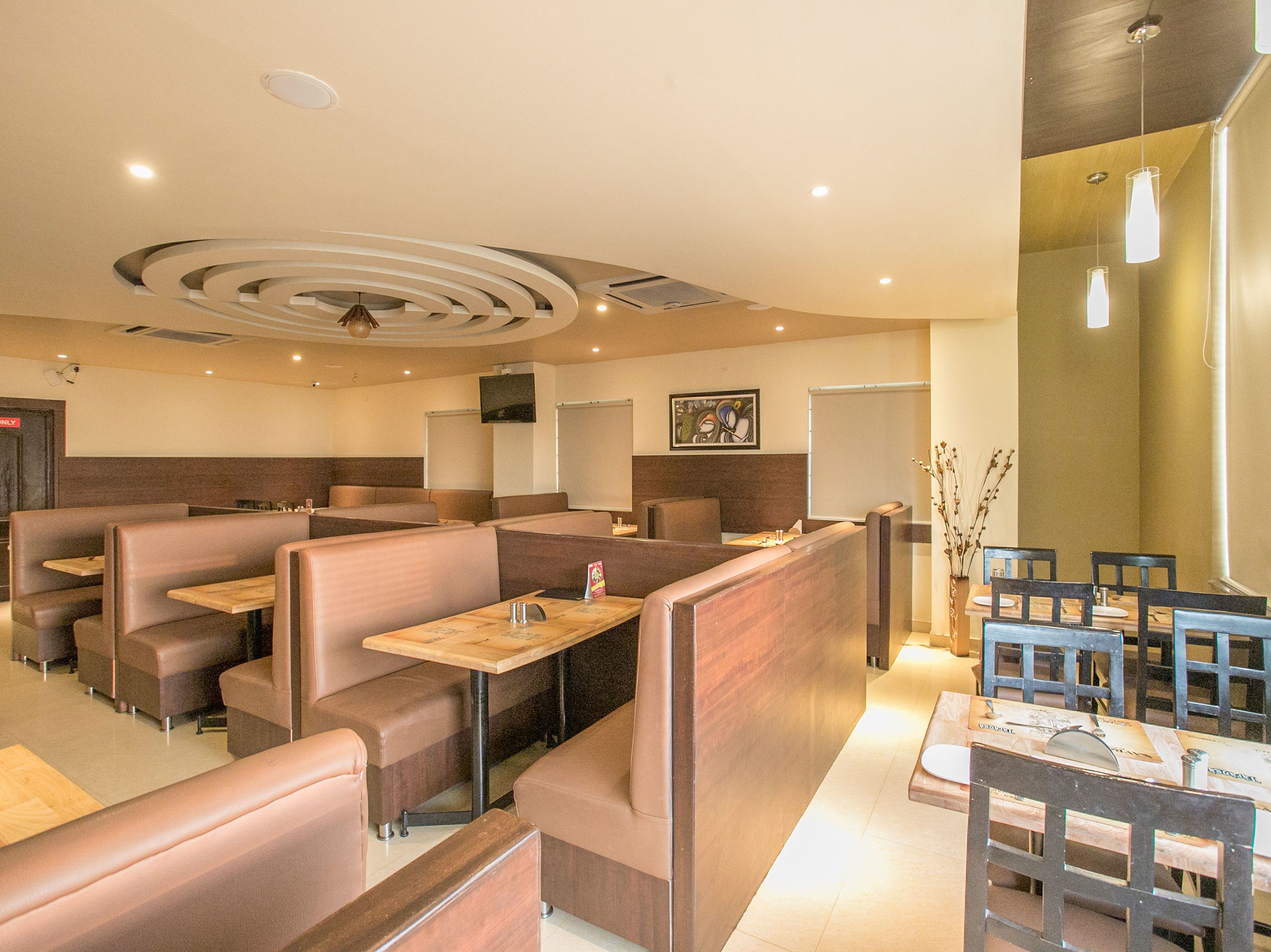 A restaurant with booth seating, tables, and a modern ceiling design.