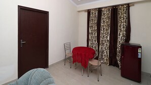 Um espaço compacto com área de jantar, uma porta, um pequeno frigorífico e cortinas estampadas.