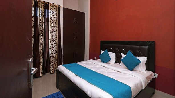 Quarto com cama, guarda-roupa e parede vermelha.