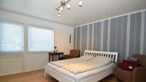 Un dormitorio con una cama individual, una mesita de noche, una silla y una lámpara.