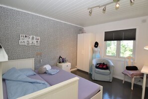 A bedroom with a bed, a chair, a wardrobe, and a window with blinds. - Solferie Holiday Home Tornestien (Kristiansand)