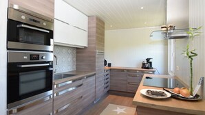 Una cocina moderna con hornos integrados, una cafetera y una planta de bambú.