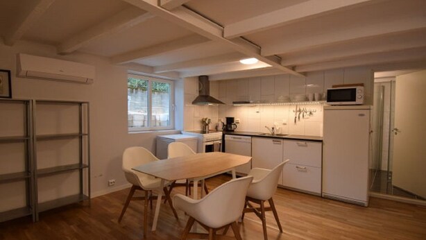 A modern kitchen with white cabinetry, a wooden dining table, and chairs. - Solferie Holiday Apartment Østerveien (Kristiansand)