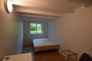 A small, narrow room with a single bed, a window, and a small table. - Solferie Holiday Apartment Østerveien (Kristiansand)