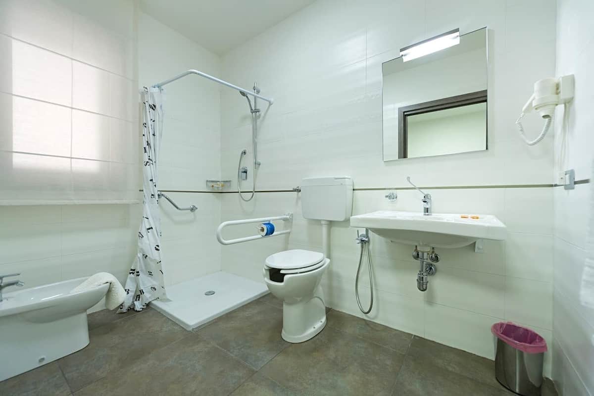 A bathroom with a shower, toilet, sink, and bidet.