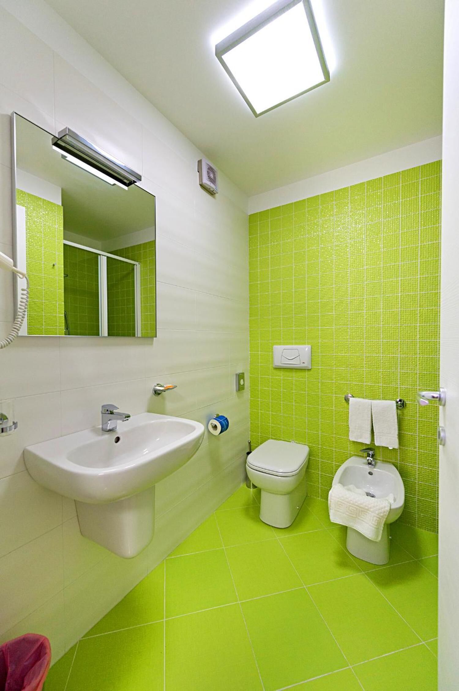 A bathroom with a sink, toilet, bidet, and a mirror.