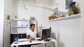 Un bureau moderne avec un bureau, un ordinateur et une chaise. On y trouve une étagère avec des objets décoratifs et une horloge au mur.