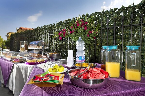 A buffet table with various food items and beverages, a water bottle, and a decorative plant in the background.