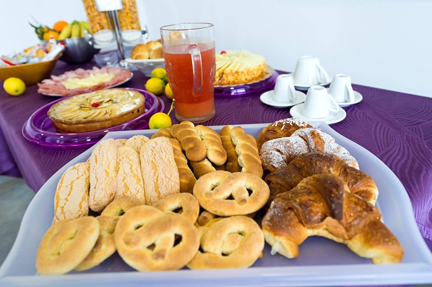 Ein Tisch mit verschiedenen Backwaren, einem Kuchen und einer Tasse Tee.