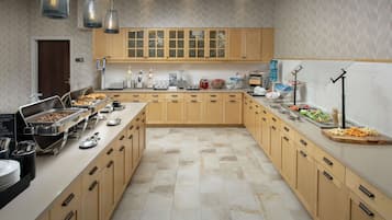 A spacious kitchen with wooden cabinets, a buffet setup, and various food items.