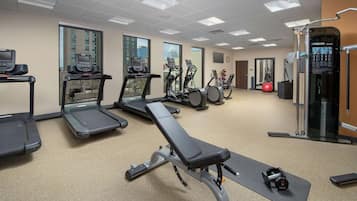 A gym with treadmills, elliptical machines, a bench, and weightlifting equipment.