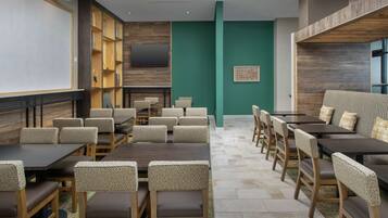 A conference room with tables and chairs, a fireplace, and a television on the wall.