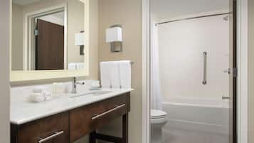 A modern bathroom with a white sink, mirror, and a shower area.