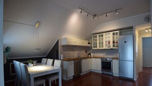 Eine kleine Küche mit weißen Schränken, ein Essbereich mit Tisch und Stühlen sowie ein eingebauter Backofen.