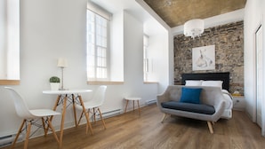 Una sala de estar moderna con una pared de piedra, una chimenea y un ventanal grande.
