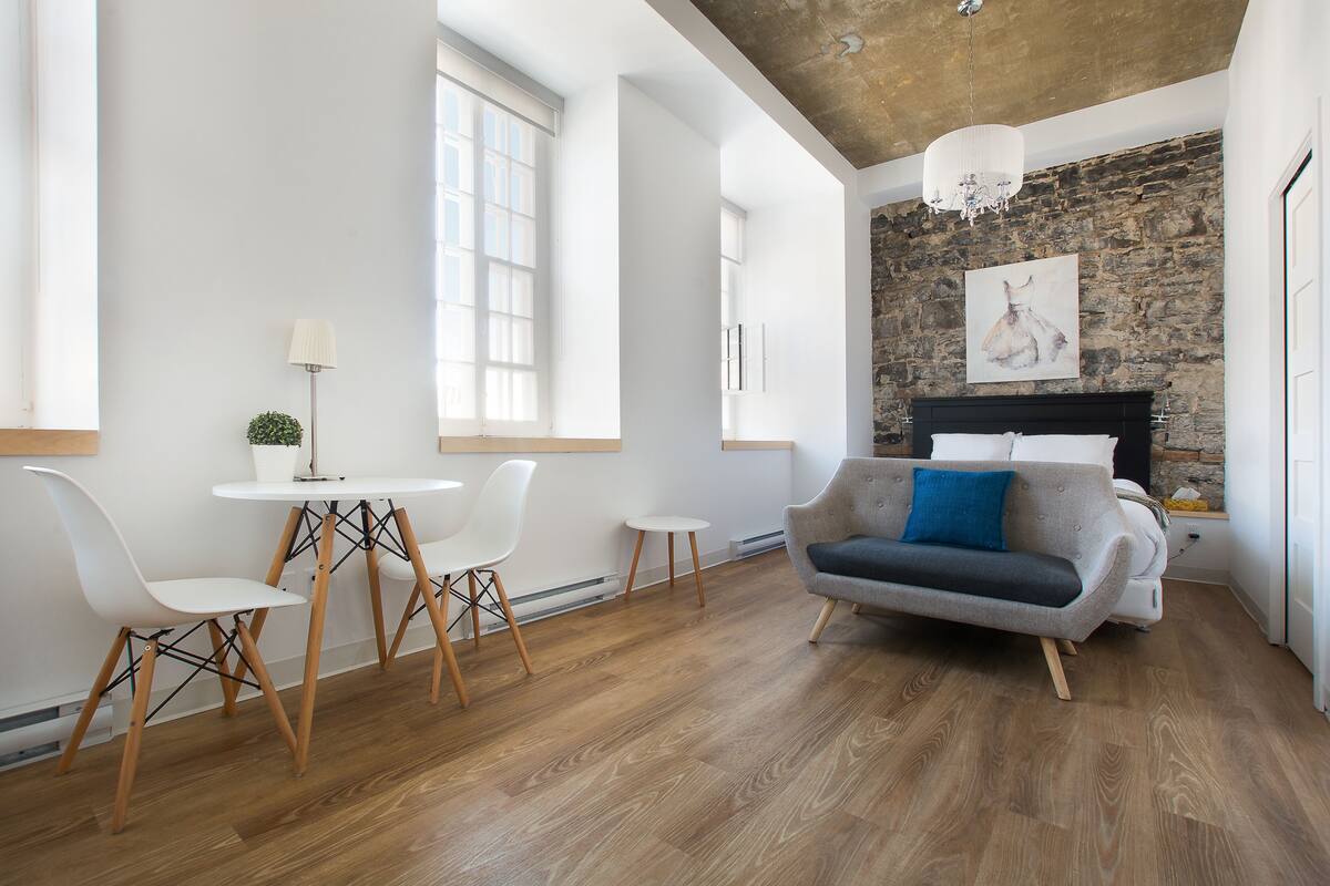A modern living room with a stone wall, a fireplace, and a large window.