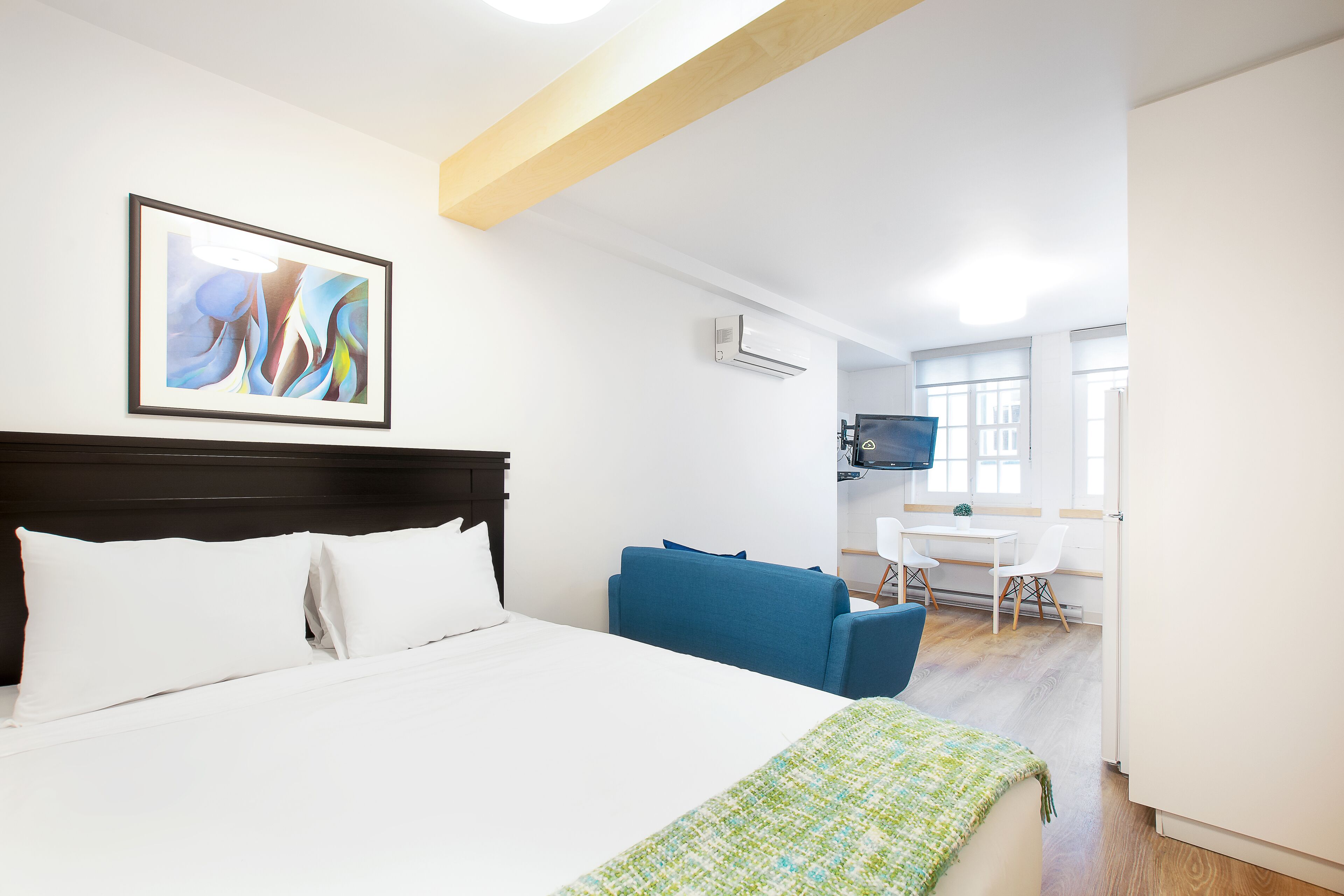 Een hotelkamer met een bed, een blauwe bank, een bureau met een stoel en een televisie aan de muur.