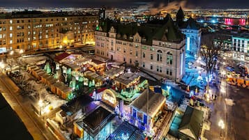 A historic building with multiple levels and a large central courtyard, surrounded by snow-covered streets and illuminated by festive lights.