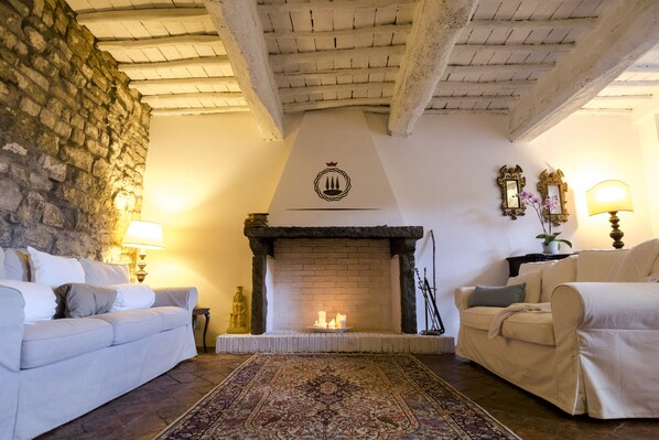 A cozy living room with a fireplace, two sofas, a rug, and a stone wall.