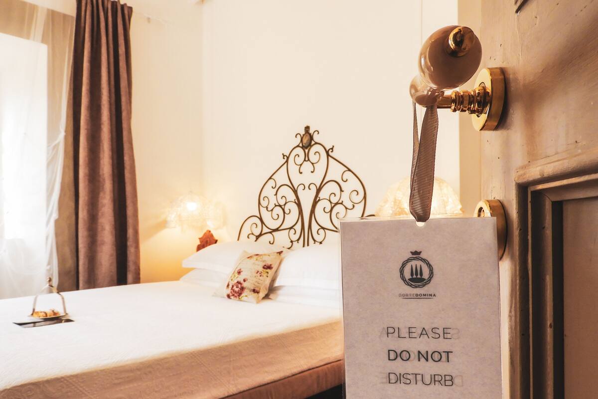 A neatly made bed with a decorative headboard, a bedside lamp, and a 'Please Do Not Disturb' sign.