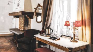 A room with a wooden bench, a table with a lamp, a chair, and a mirror on the wall.