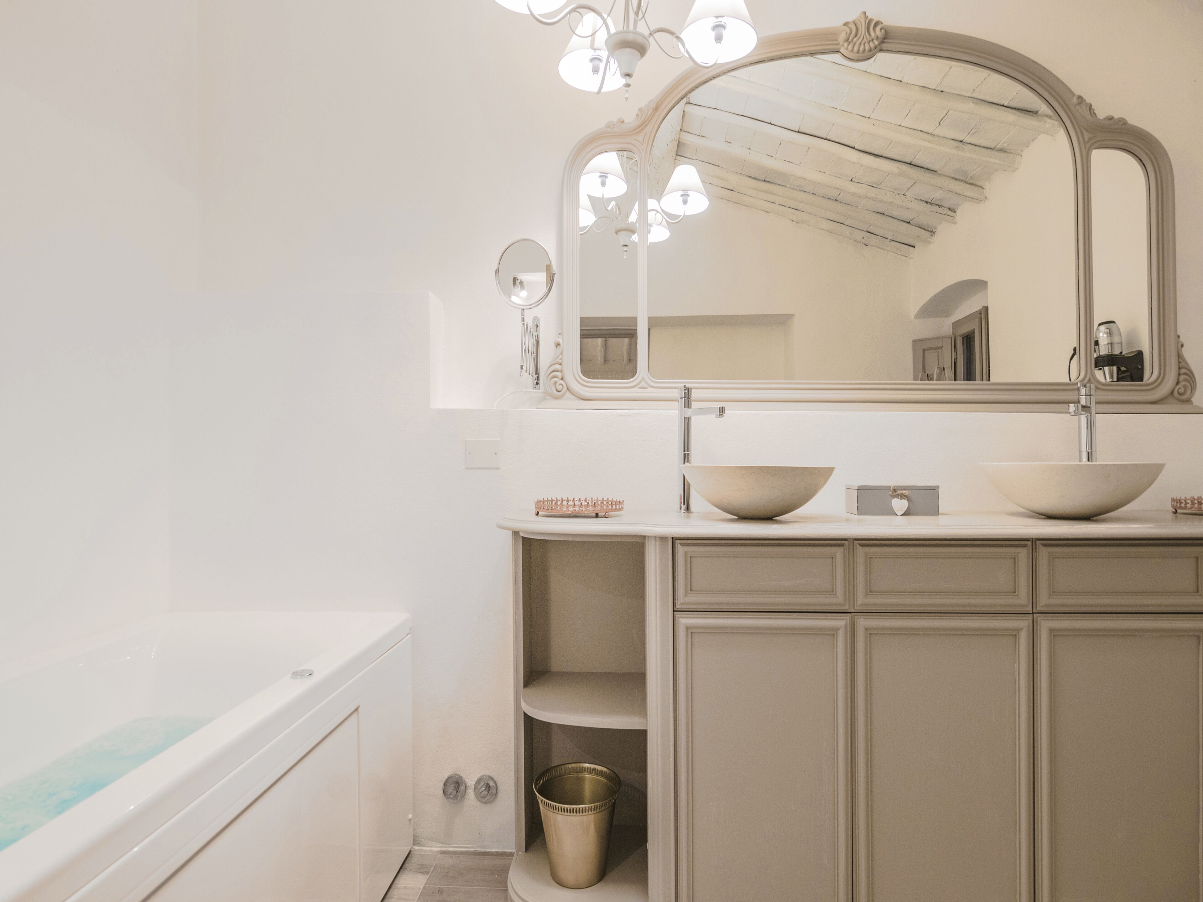 A bathroom with a white bathtub, a large mirror, and a sink with two bowls.